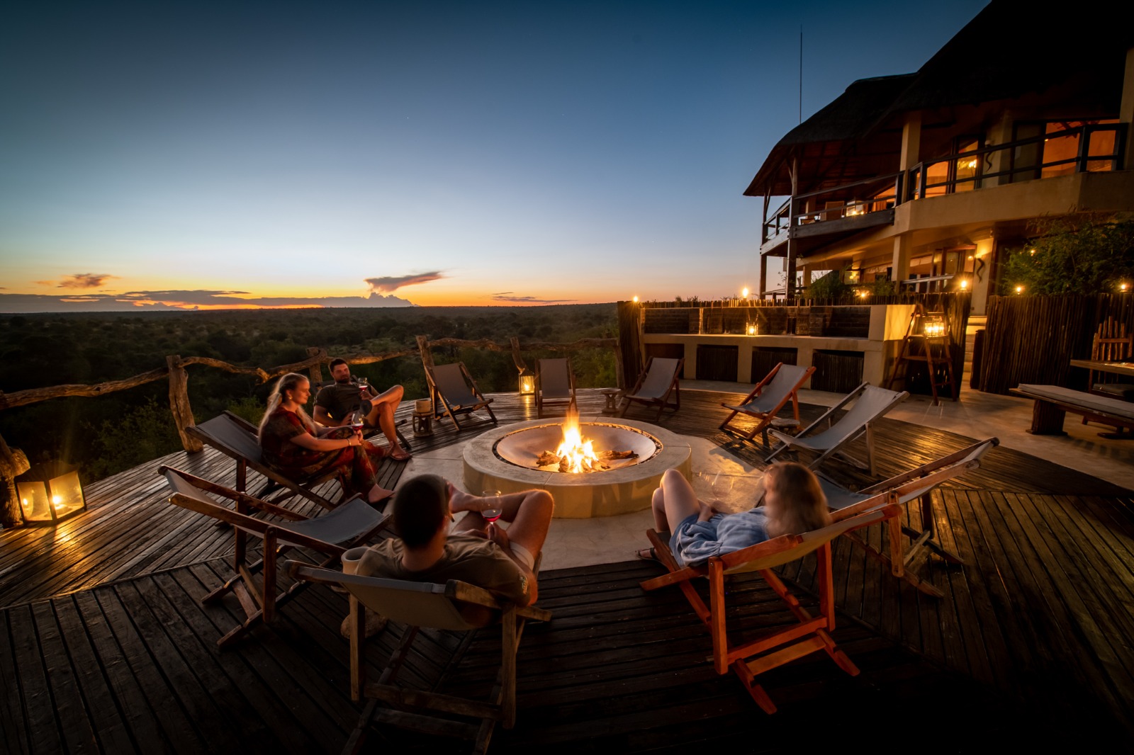 Guests relaxing around the fire pit at Makumu Private Game Lodge at dusk