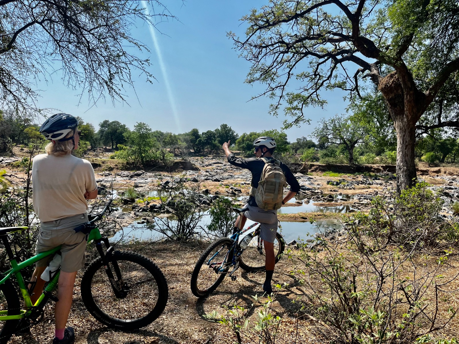 Cyclists pausing at a dry riverbed on an Outland Travel cycle safari